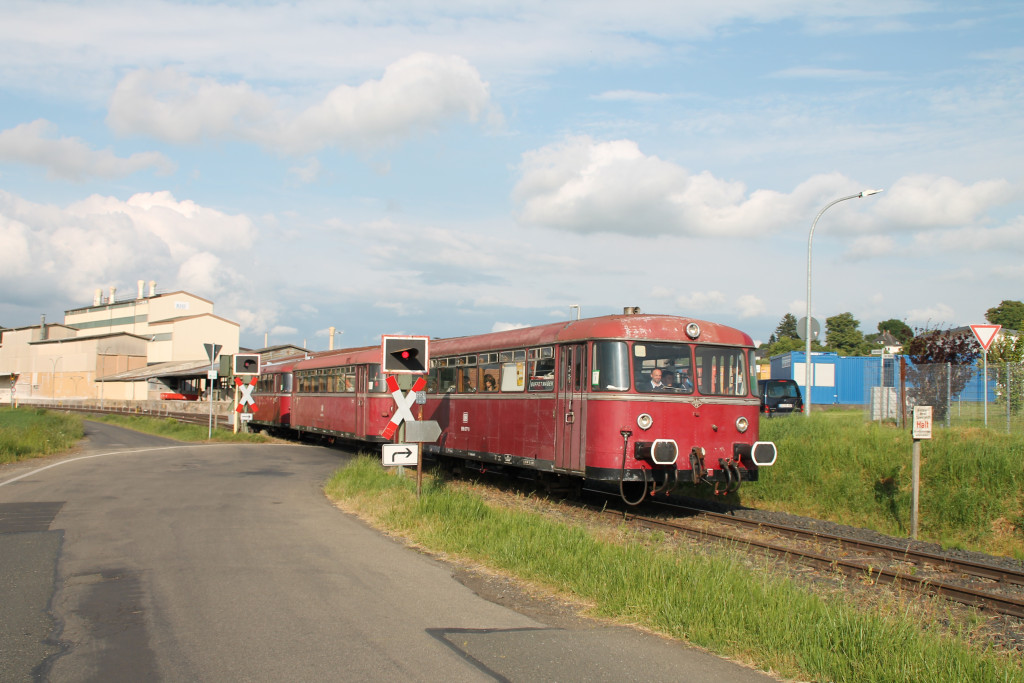 996 677 erreicht am 25.05.2015 mit seiner dreiteiligen Schienenbusgarnitur einen Bahnübergang in Mainzlar auf der Lumdatalbahn.