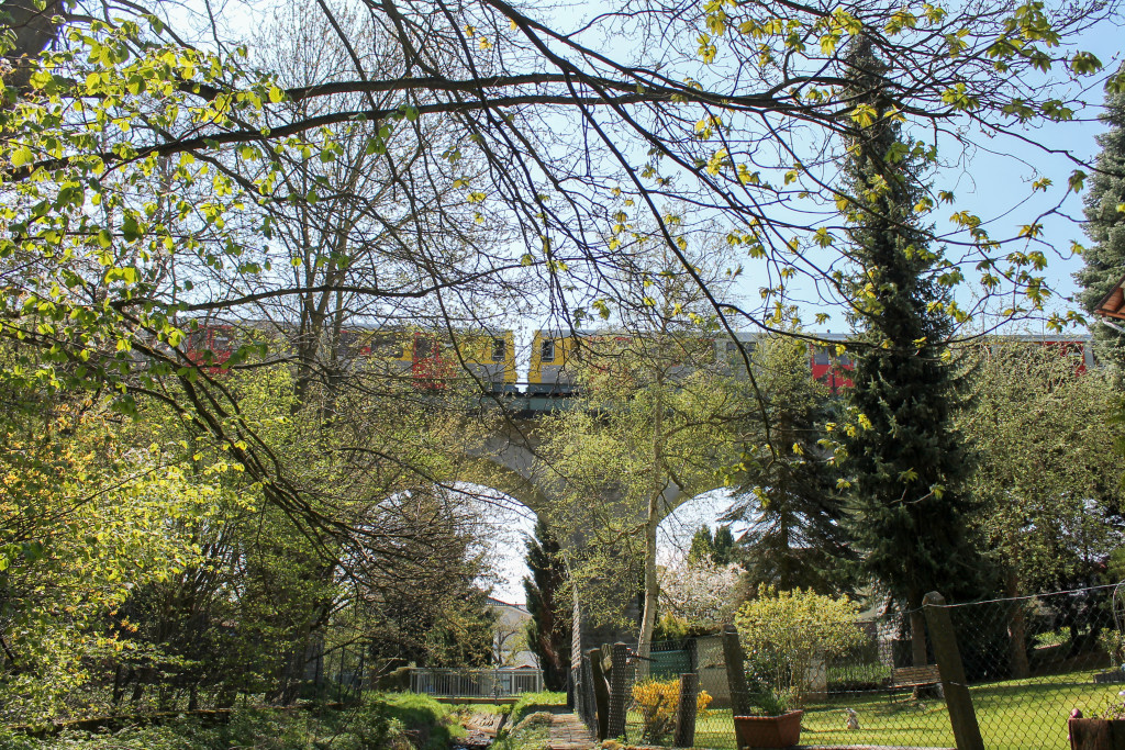 Zwei VT2E der HLB überqueren hinter den Bäumen das Viadukt in Neu-Anspach auf der Taunusbahn, aufgenommen am 23.04.2015.