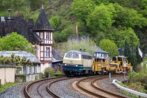 215 004 überführt eine Baumaschine durch Balduinstein auf der Lahntalbahn, aufgenommen am 22.04.2017.