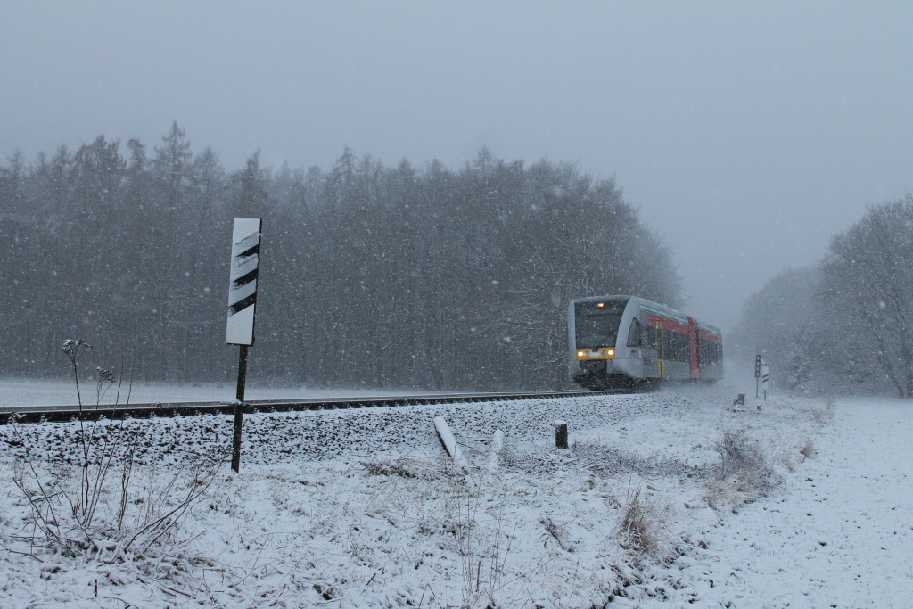 Im Schneetreiben am 24.01.2015 passiert ein GTW 2/6 der HLB den ehemaligen Bahnübergang zwischen Lich und Langsdorf auf der Lahn-Kinzig-Bahn.