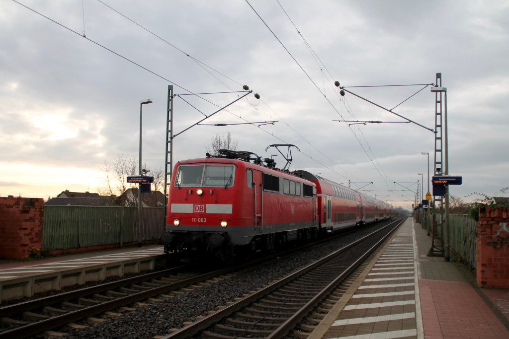 111 063 legt mit ihrem Zug aus Doppelstockwagen einen kurzen Halt in Bürstadt auf der Riedbahn ein, aufgenommen am 21.11.2015.